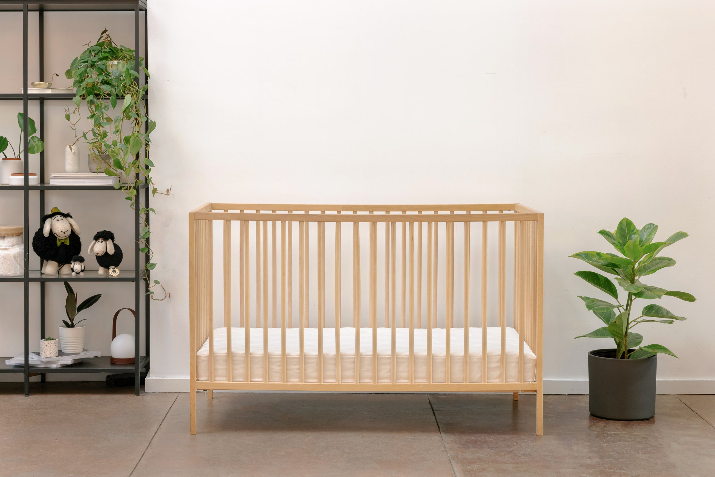 Crib with natural latex mattress inside. Natural decor like wool sheep toys on the side.
