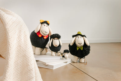 Handmade decorative wool sheep on the floor beside a natural mattress and organic cotton blanket.