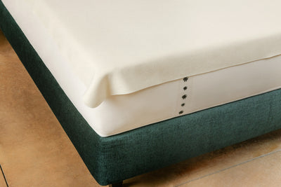Corner of wool mattress protector on top of mattress and platform base