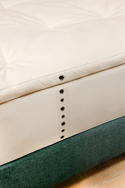 Close up of wool mattress topper on top of hybrid mattress