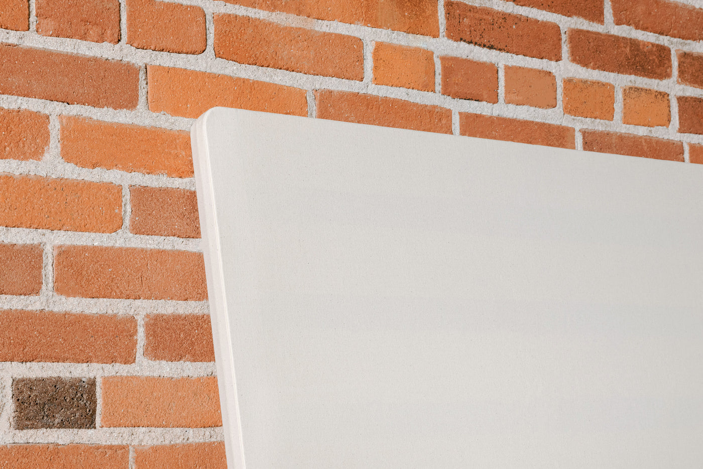 Corner of upholstered bunkie board against brick wall