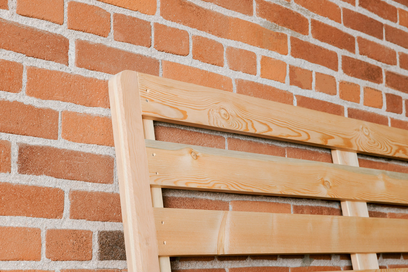 Corner of wooden bunkie board against brick wall