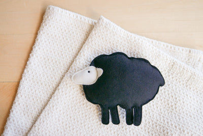 Organic cotton waffle blanket with a wool sheep toy on top